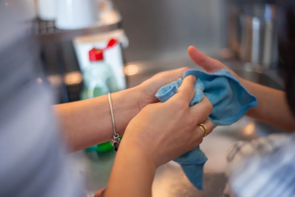 Une personne entièrement équipée d’un EPI désinfecte une table à l’intérieur pour l’hygiène et la sécurité.